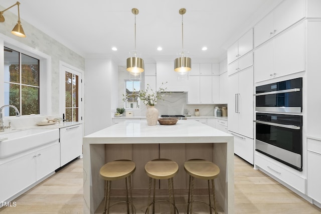 kitchen with white cabinetry, stainless steel appliances, sink, and a kitchen island