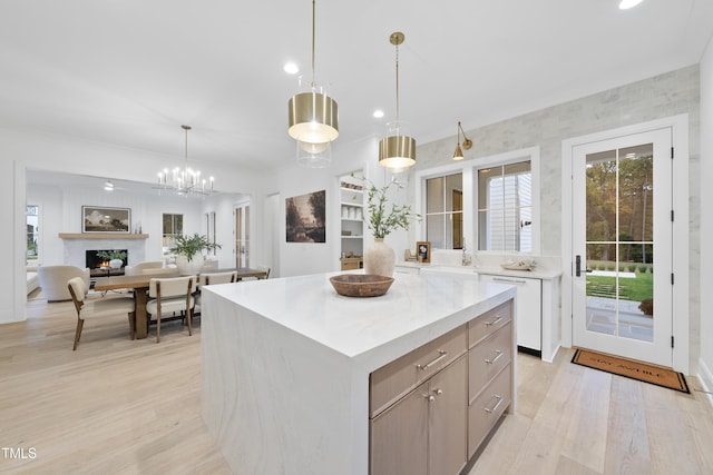 kitchen with light hardwood / wood-style floors, dishwasher, hanging light fixtures, and a kitchen island