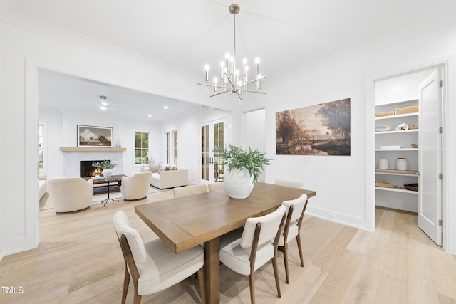 dining space with crown molding, an inviting chandelier, and light hardwood / wood-style flooring