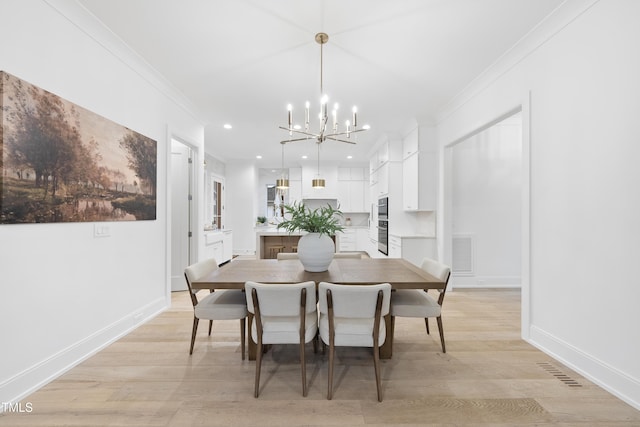 dining space with a notable chandelier, ornamental molding, and light wood-type flooring