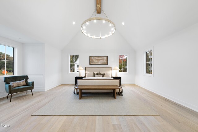 bedroom with light hardwood / wood-style flooring, high vaulted ceiling, and a chandelier