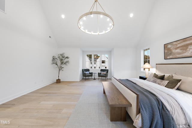 bedroom featuring multiple windows, an inviting chandelier, high vaulted ceiling, and light hardwood / wood-style flooring