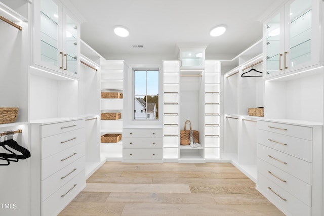 walk in closet with light hardwood / wood-style floors