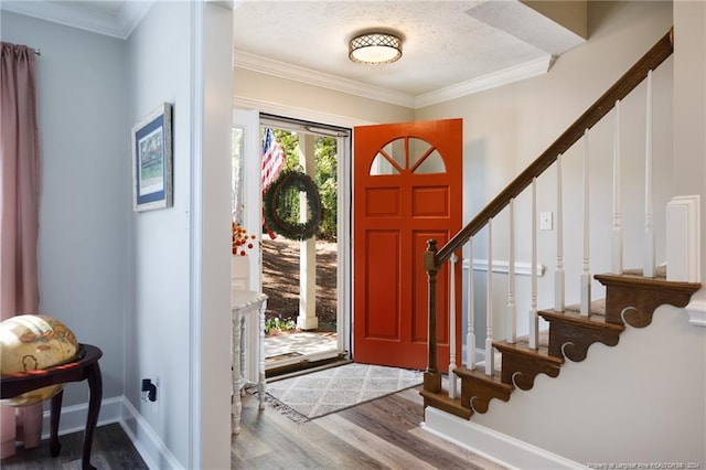 entryway with wood-type flooring, crown molding, and a textured ceiling