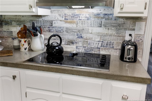 kitchen featuring white cabinets, tasteful backsplash, fume extractor, and black electric stovetop