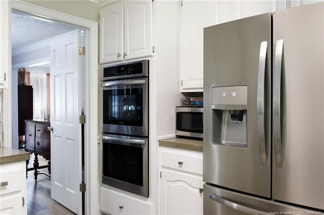 kitchen featuring hardwood / wood-style floors, crown molding, white cabinetry, and stainless steel appliances