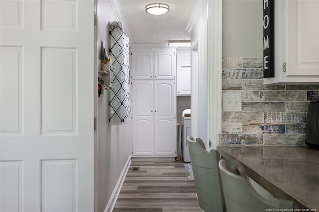 interior space with cabinets, crown molding, a textured ceiling, dark wood-type flooring, and washer / clothes dryer