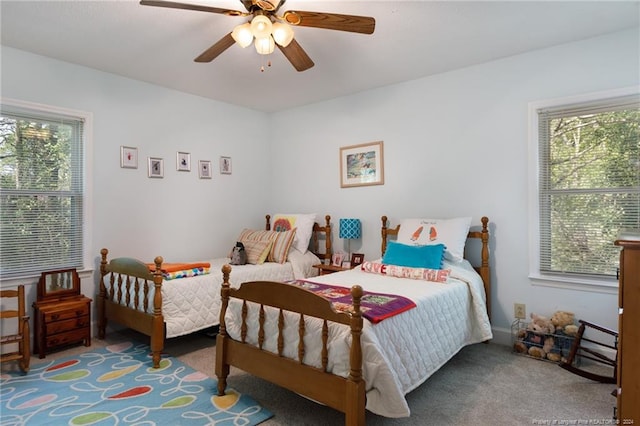 carpeted bedroom featuring multiple windows and ceiling fan