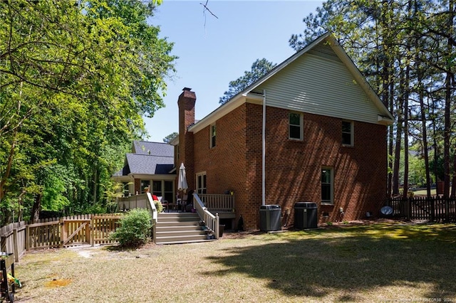 back of property featuring central AC unit and a lawn