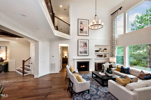 living room featuring dark wood-type flooring, a towering ceiling, and crown molding