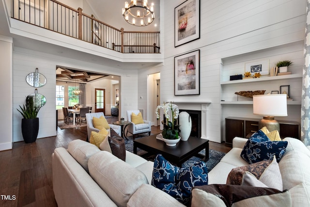 living room featuring dark hardwood / wood-style floors, a notable chandelier, a towering ceiling, and wooden walls