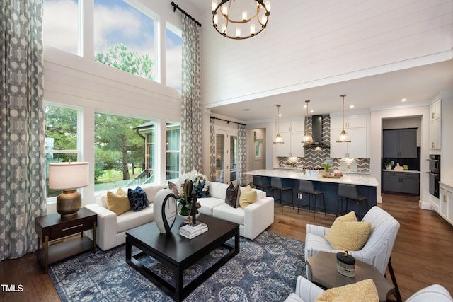 living room with dark hardwood / wood-style flooring, a towering ceiling, and an inviting chandelier