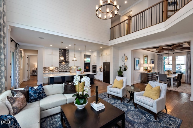 living room with dark hardwood / wood-style flooring, ornamental molding, beamed ceiling, and an inviting chandelier