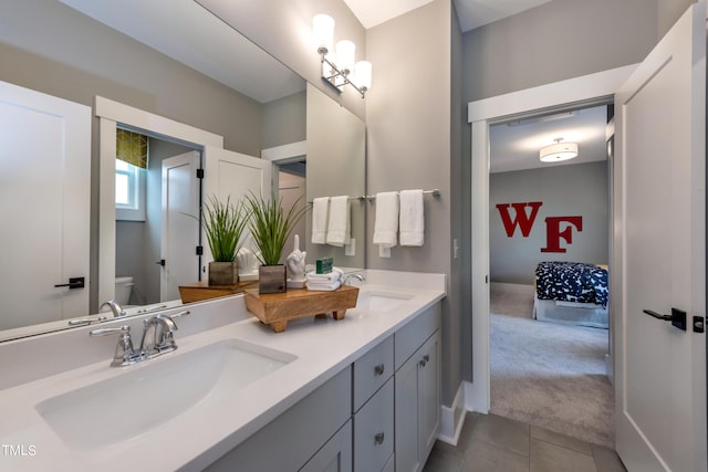 bathroom with toilet, vanity, and tile patterned floors