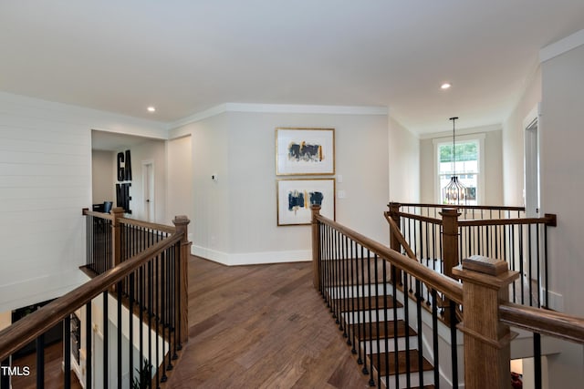 hallway with dark hardwood / wood-style floors, crown molding, and a notable chandelier