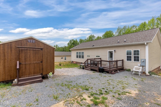 rear view of house with a wooden deck and a storage shed