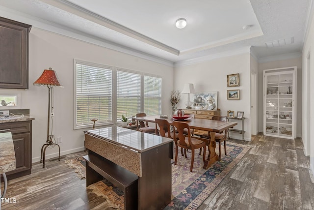 dining area featuring ornamental molding, dark hardwood / wood-style floors, and a raised ceiling