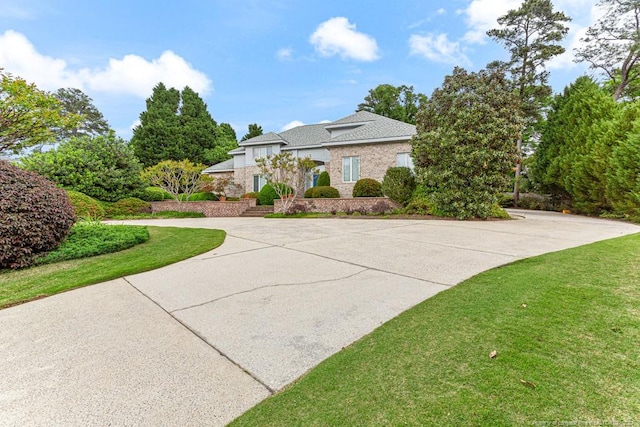view of side of property with a lawn and curved driveway
