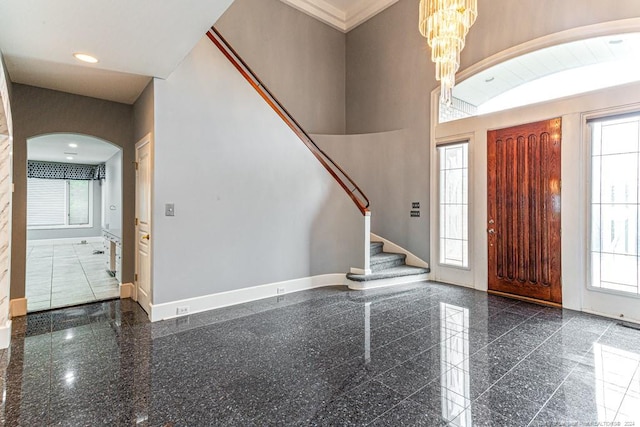 foyer featuring arched walkways, baseboards, granite finish floor, and stairway
