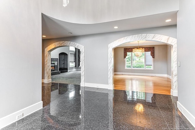 foyer with recessed lighting, baseboards, a glass covered fireplace, and granite finish floor