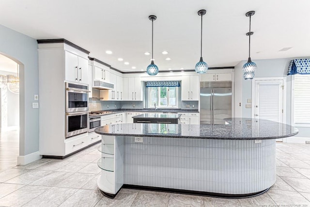 kitchen with appliances with stainless steel finishes, pendant lighting, tasteful backsplash, and light tile patterned flooring