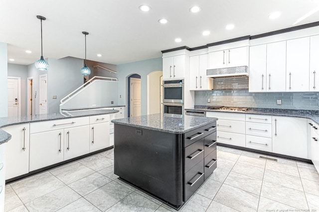 kitchen with tasteful backsplash, stainless steel appliances, hanging light fixtures, light tile patterned floors, and dark stone countertops