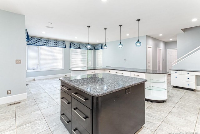 kitchen featuring light tile patterned floors, pendant lighting, light stone counters, and a kitchen island