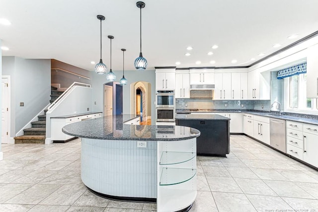 kitchen with tasteful backsplash, hanging light fixtures, a center island, appliances with stainless steel finishes, and light tile patterned floors