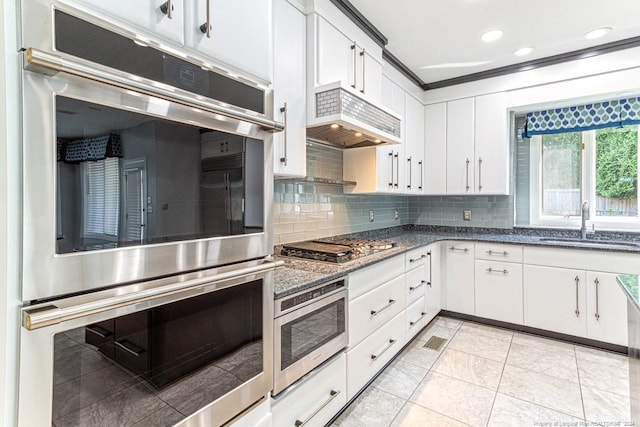 kitchen with white cabinets, custom exhaust hood, appliances with stainless steel finishes, decorative backsplash, and sink