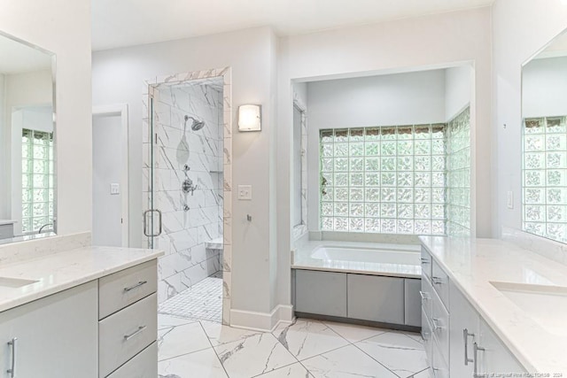 bathroom featuring a garden tub, marble finish floor, two vanities, a sink, and a stall shower
