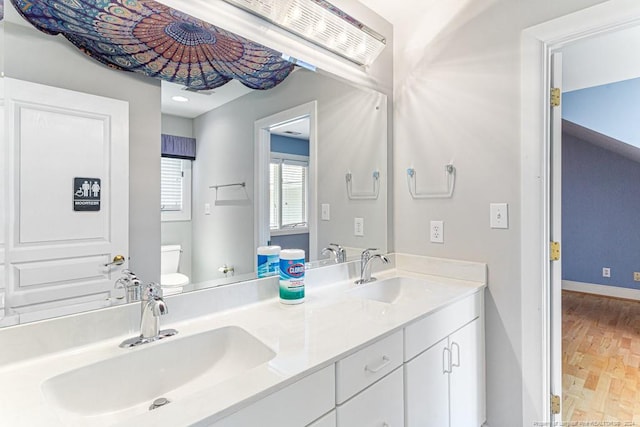 bathroom featuring wood-type flooring, double sink vanity, and toilet