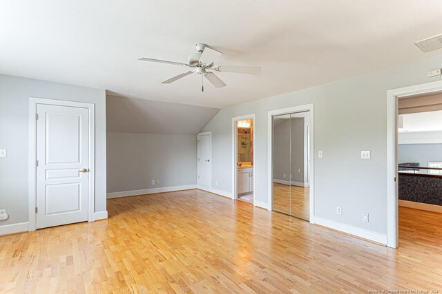 interior space with light hardwood / wood-style flooring, ensuite bath, lofted ceiling, and ceiling fan