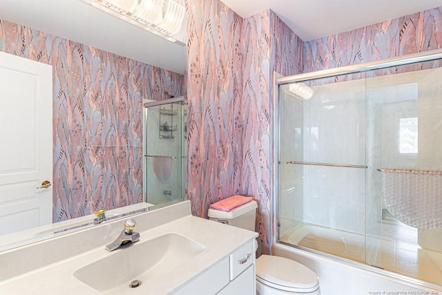 bathroom featuring vanity, enclosed tub / shower combo, and toilet
