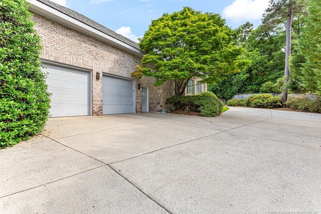 view of home's exterior featuring brick siding, a garage, and driveway
