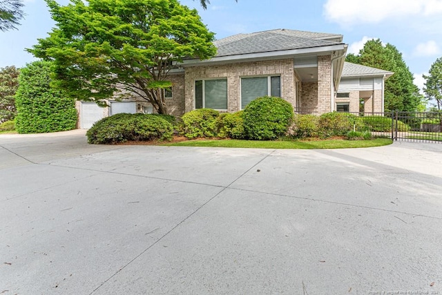 view of property exterior with brick siding, fence, driveway, and a garage