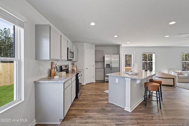 kitchen with a breakfast bar area, recessed lighting, dark wood-style flooring, appliances with stainless steel finishes, and open floor plan