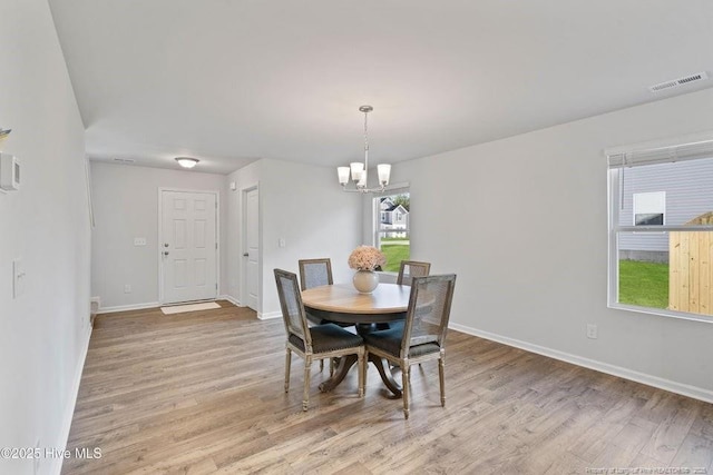 dining room featuring an inviting chandelier, light wood-style flooring, baseboards, and visible vents