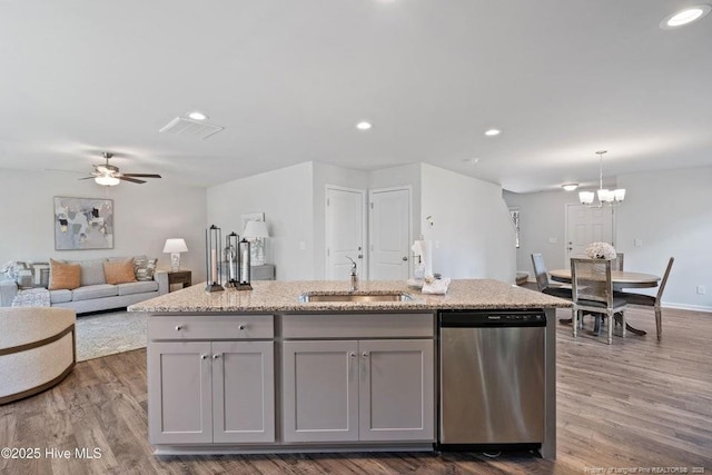 kitchen featuring a center island with sink, dishwasher, gray cabinetry, and a sink