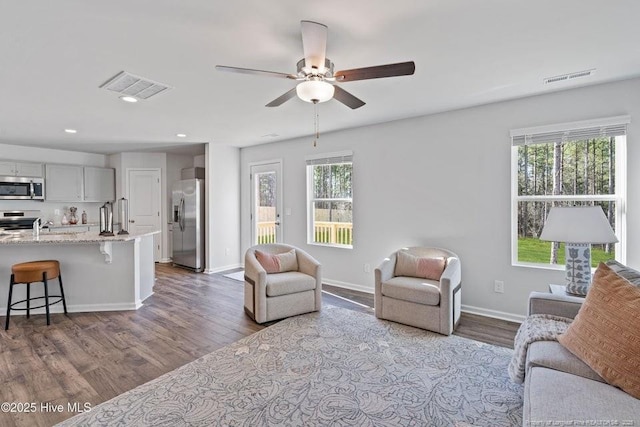 living room featuring dark wood finished floors, visible vents, and plenty of natural light