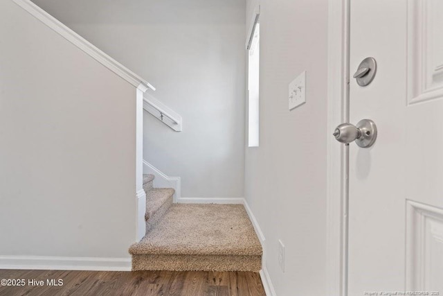 staircase featuring baseboards and wood finished floors