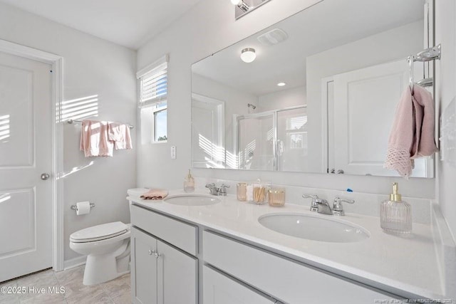 full bath featuring double vanity, a shower stall, toilet, and a sink