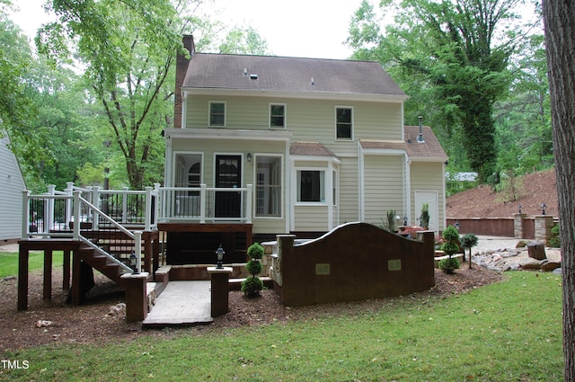 rear view of property with a sunroom, a wooden deck, and a lawn