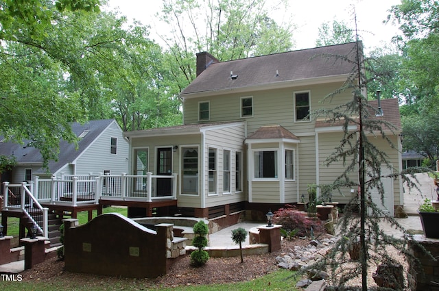 back of property with a wooden deck and a sunroom