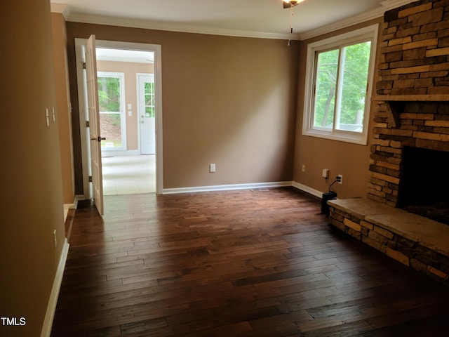 unfurnished living room with a fireplace, dark wood-type flooring, crown molding, and brick wall