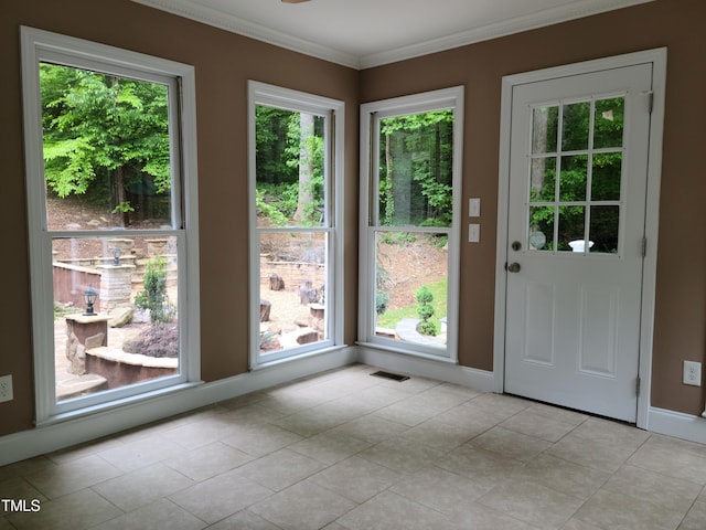 doorway with crown molding and light tile floors