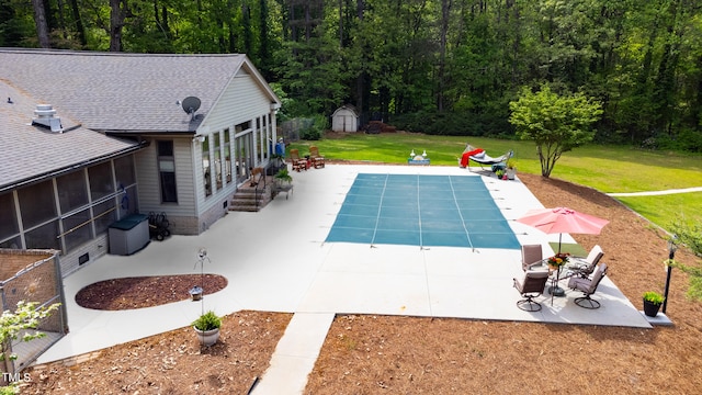 view of swimming pool with a yard, a storage unit, a sunroom, and a patio