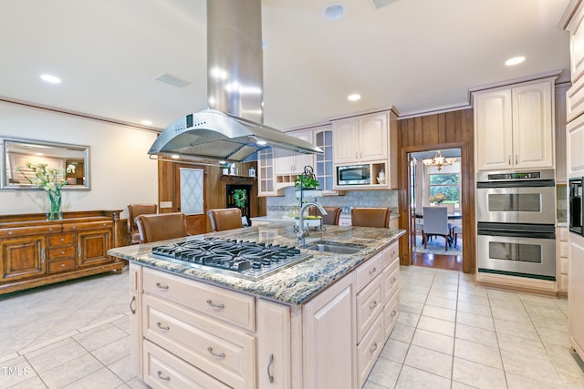 kitchen featuring stainless steel appliances, crown molding, island range hood, a center island with sink, and sink