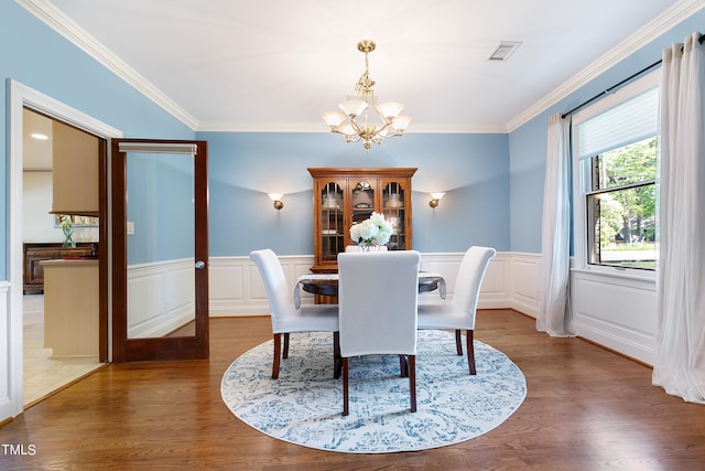 dining space featuring hardwood / wood-style flooring, ornamental molding, and an inviting chandelier