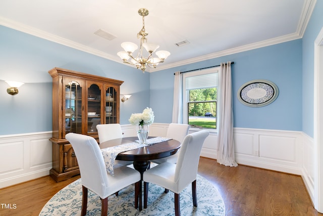 dining space with crown molding, a notable chandelier, and hardwood / wood-style floors