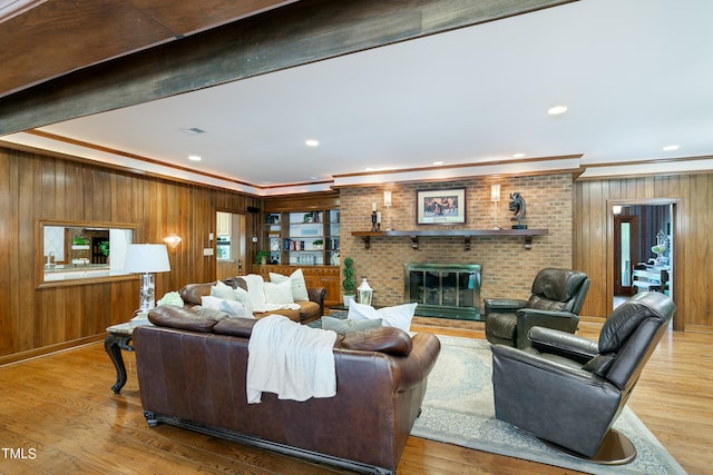 living room with wooden walls, brick wall, light hardwood / wood-style floors, and a brick fireplace